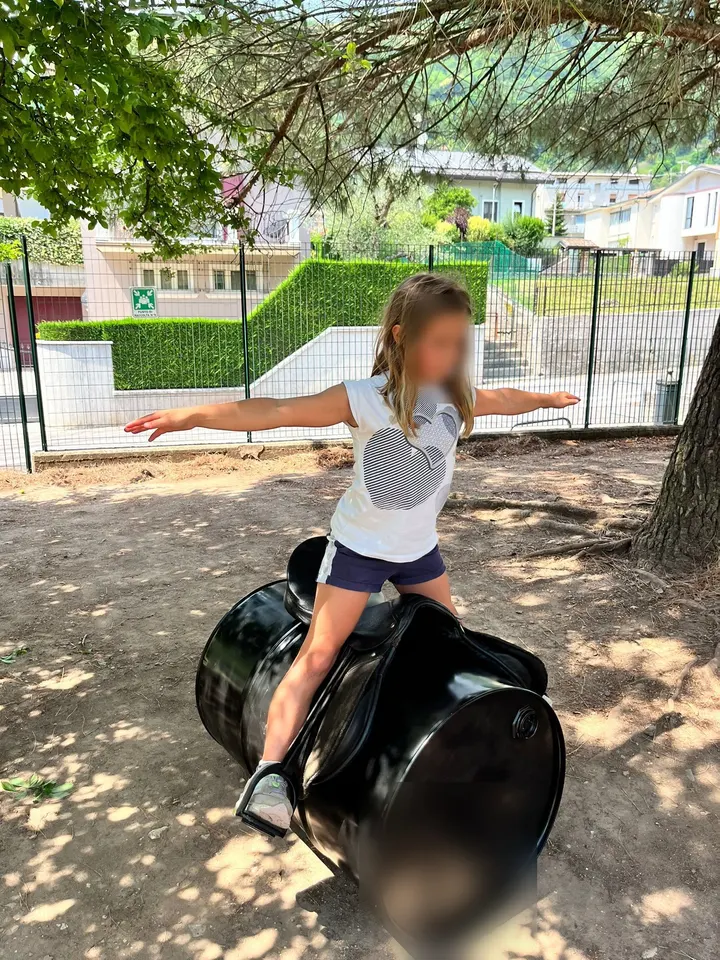 Bambina in equilibrio, a braccia aperte, durante un gioco