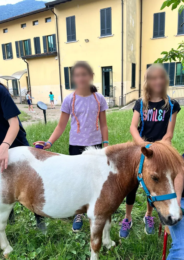 Due ragazze sorridono accanto al pony